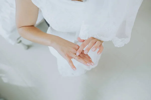 Mãos dedo anel de noiva dobrado contra vestido de noiva branco — Fotografia de Stock