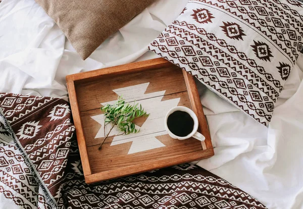 Kopje koffie op een dienblad met een groene tak in de slaapkamer — Stockfoto