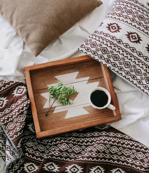 Kopje koffie op een dienblad met een groene tak op het bed — Stockfoto