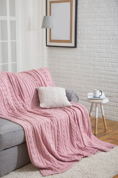 Sofa z pink plaid we wnętrzu w pobliżu okna — Zdjęcie stockowe