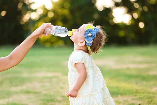 Küçük kız içecekler su şişesi anneler el — Stok fotoğraf