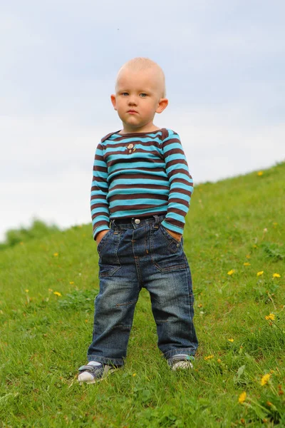 Маленькие джинсы для мальчиков стоят у весенних карманов для рук — стоковое фото