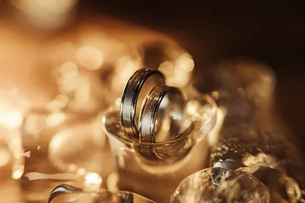 pair of gold wedding rings on ice cubes sparkle and reflection