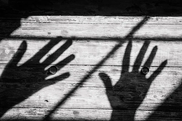 shadow two hands inside window wooden background