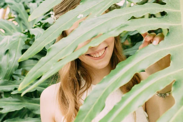Rosto menina espreita através de folhas de palma trópicos — Fotografia de Stock