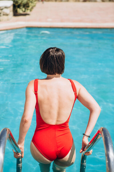 Brunette woman red bathing suit ladder pool — Stock Photo, Image