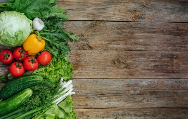 Taze sebzeler ahşap arka planda sol tarafta. Yazıtlar için boş bir yer.