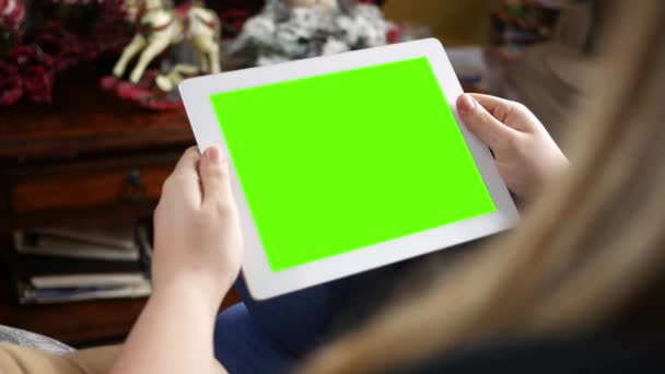 Brunette jeune femme regarde une tablette écran vert dans le salon 