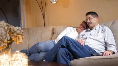 Orta yaşlı çift Tv Alt komik film izlerken modern oturma odasında kanepede