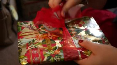 Kadın papyon hediye Noel zamanı çevresinde unwraps - yakın çekim