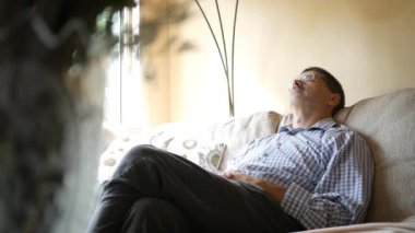 Orta yaşlı beyaz bir kanepede gün boyunca bir şekerleme alarak erkek