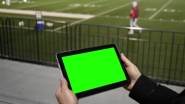 男子观看绿屏平板电脑在橄榄球队练习会议从露天看台 — 图库视频影像
