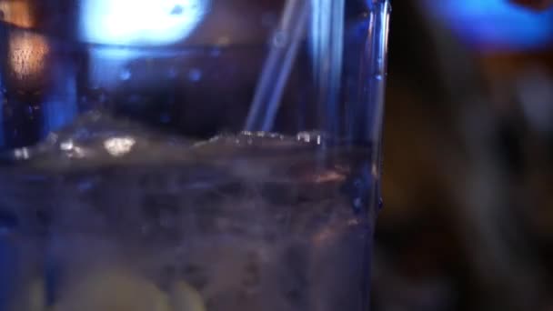 暗いレストランで氷の水のガラスを攪拌 — ストック動画