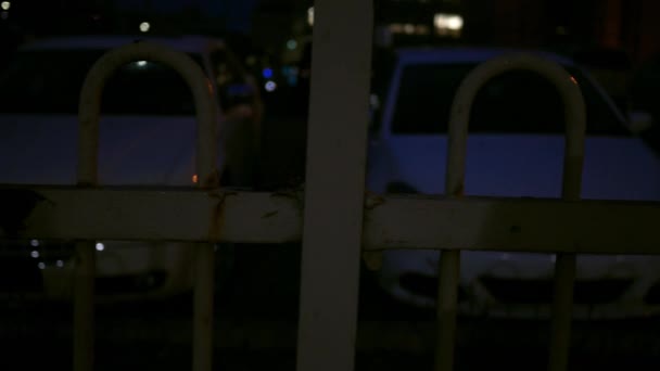 Panning Car Parking Lot Fence Foreground Night Metropolitan Area — Stock Video