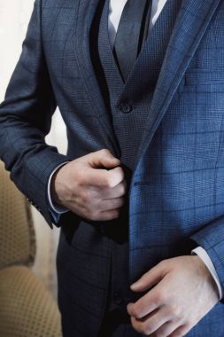 Damat, ceketini bir düğme ayarlar. Papyon ceketle ellerini tutarak damat