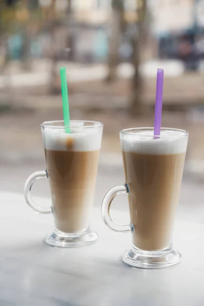 Cappuccino, latte art a fehér fából készült asztal két üveg pohár — Stock Fotó