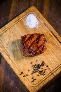 Ahşap tahta çatal ve bıçak otlar baharatlar ve tuz ile sığır eti biftek