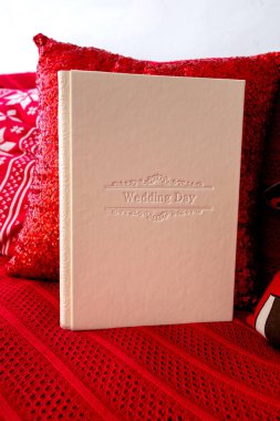 Ahşap arka planda bir kutulu fotoğraf albümü. Kabartmalı fotoğraf kitabı. Hediye kutusu olan bir fotobook Sert kapaklı parlak kırmızı fotoğraf albümüyle fotoğraf albümü.