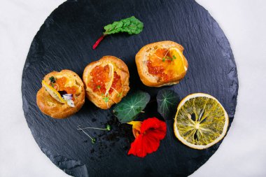 Tereyağlı ve kırmızı havyarlı sandviçler, yeşilliklerle süslenmiş, limon dilimleri, nane yaprağı, yanında tereyağlı bir tabak ve yanında havyarlı bir kaşık.