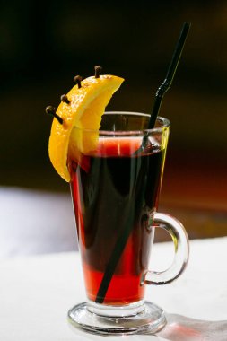 Beyaz arka planda bir dilim portakalla süslenmiş bir bardakta şenlendirilmiş şarap.