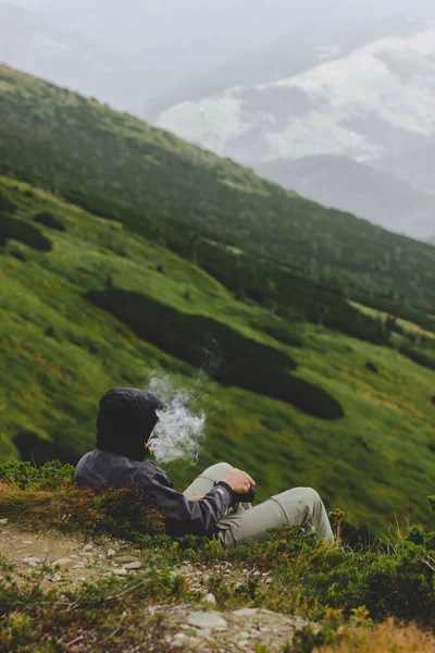 Gezgin dağlardaki arayan bir cigarete sigara içiyor.