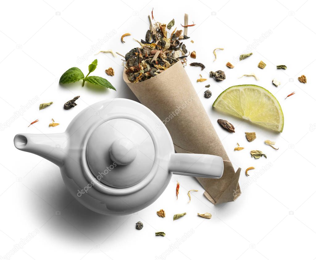 Green tea with natural aromatic additives and a teapot. Top view on white background