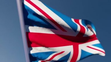 Büyük Britanya 'nın ulusal bayrağı mavi gökyüzüne karşı rüzgarda dalgalanıyor.
