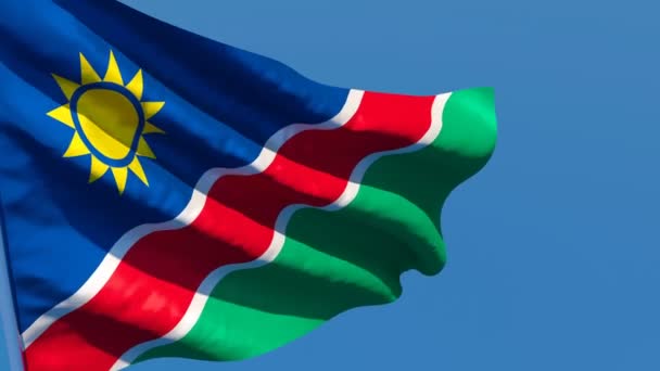 Namibya 'nın ulusal bayrağı mavi gökyüzüne karşı rüzgarda dalgalanıyor. — Stok video