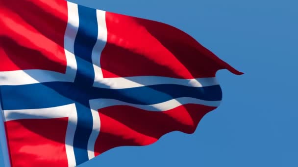 Norvégia nemzeti zászlaja a szélben a kék égbolttal szemben röpköd — Stock videók