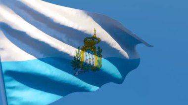 San Marino 'nun ulusal bayrağı mavi gökyüzüne karşı rüzgarda dalgalanıyor.