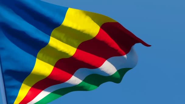 Seychellernas nationella flagga fladdrar i vinden mot en blå himmel — Stockvideo