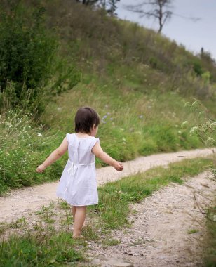 bir çocuk yalınayak kumlu yolda yürüyor