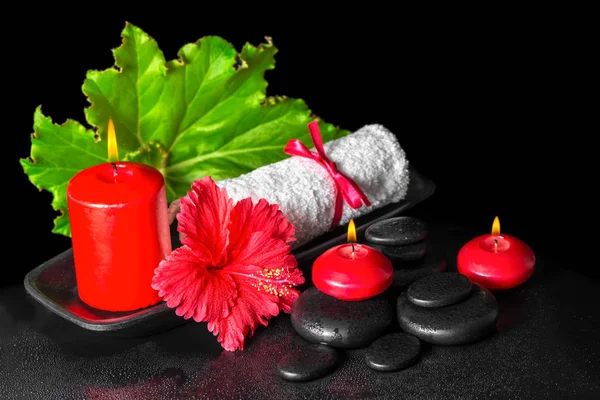 beautiful spa concept of red hibiscus flower with dew, candles,
