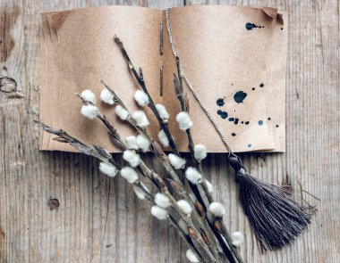 Söğüt dalları, el yapımı kitap ve ahşap masa üzerinde püsküllü düz kompozisyon.