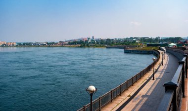 Angara Nehri 'nin setinden Irkutsk manzarası. Gezinti alanı olan bir rıhtım. Uzakta bir tapınak var..