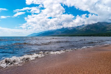 Baykal dalgaları kumsala vurdu. Bulutlu gökyüzü ile Kutsal Burun 'un yarımadasının manzarası. Barguzinsky Körfezi, Buryatia Cumhuriyeti, Rusya.