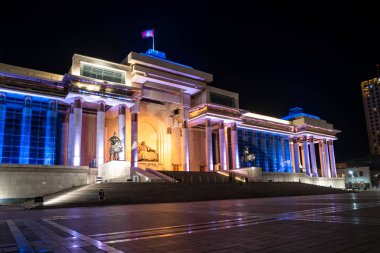 Ulaanbaatar, Mongolia - August 8, 2018: View of State History Museum of Mongolia with night illumination in Sukhbaatar Square. Statues Genghis Khan and commanders Boorchi and Muqali. clipart