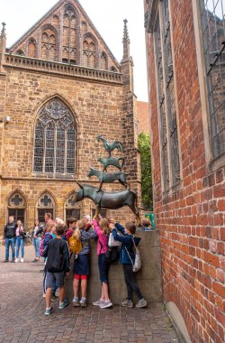 Bremen, Almanya - 28 Haziran 2019: Çocuklar Bremen Kasaba Müzisyenleri heykelinin önünde bir dilek tutarlar