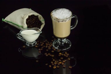 İnci keten çantasından bir kase süt ve kahve çekirdekleri ile tamamlanmaktadır latte, büyük bir bardak döküldü