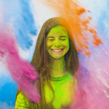 Neşeli kız patlama Holi renkler (boya) partide renkli toz altında. Hareket (durmak devinim) patlayan veya renk toz atma renk toz dondur. Çok renkli parlak patlama.