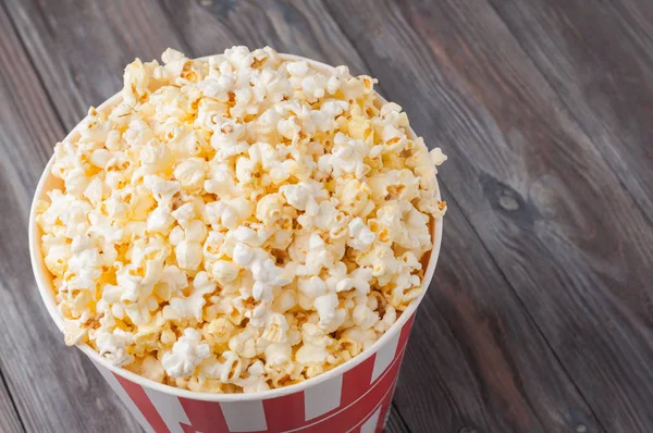 Popcorn in einem gestreiften Eimer (rot-weiße Schachtel) isoliert auf grau — Stockfoto