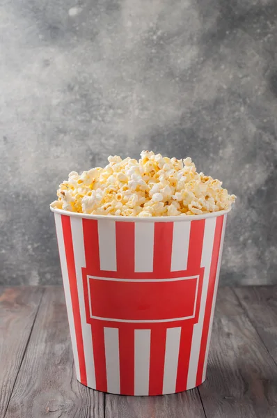 Popcorn in einem gestreiften Eimer (rot-weiße Schachtel) isoliert auf grau — Stockfoto