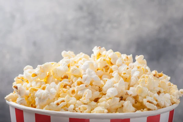 Popcorn in einem gestreiften Eimer (rot-weiße Schachtel) isoliert auf grau — Stockfoto