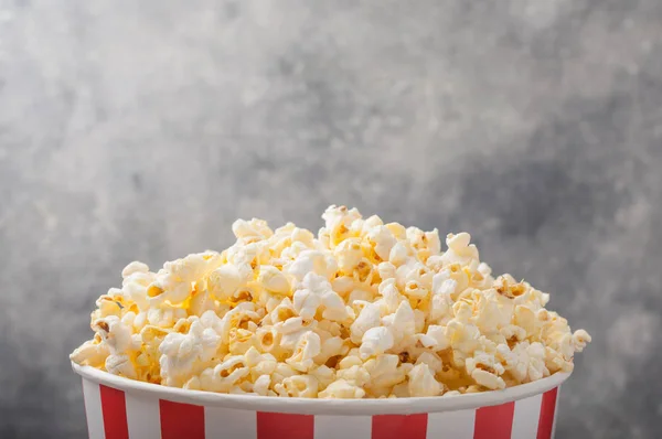 Popcorn in einem gestreiften Eimer (rot-weiße Schachtel) isoliert auf grau — Stockfoto