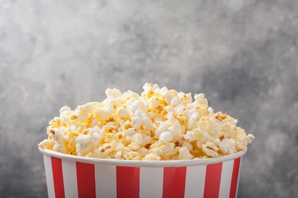Popcorn in einem gestreiften Eimer (rot-weiße Schachtel) isoliert auf grau — Stockfoto