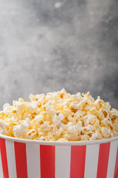 Popcorn in einem gestreiften Eimer (rot-weiße Schachtel) isoliert auf grau — Stockfoto