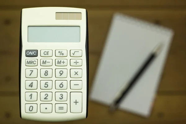 Zbliżenie z kalkulatorów na tle drewnianych z notebookiem — Zdjęcie stockowe