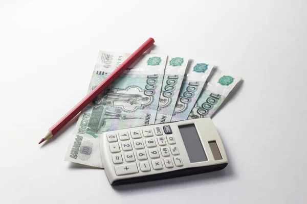 Dinero con una calculadora sobre un fondo blanco — Foto de Stock