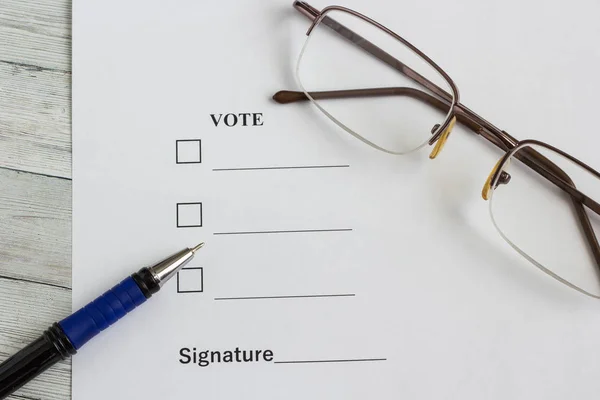 Documento para votar sobre la mesa de madera, junto a la pluma y los vasos —  Fotos de Stock
