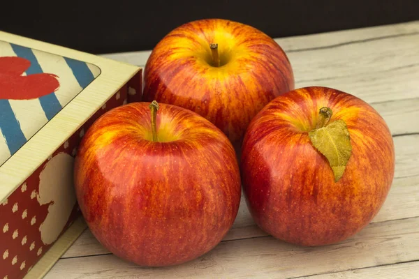 Fruits of a red apple with leaves near the gift box — Stock Photo, Image